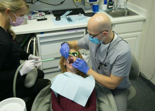 dentist working on a patient with dental assistant standing next to the patient