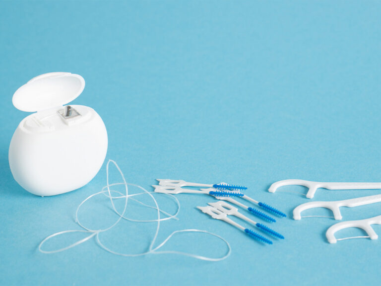 String, pick and interdental flossers on a light blue backdrop